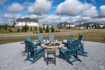 A fire pit surrounded by chairs in the middle of a gravel area